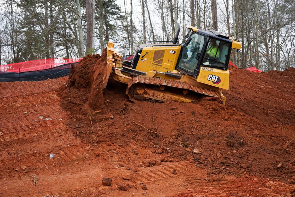 CAT D4 bulldozer moving red clay at an active construction site